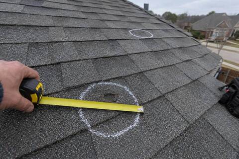 A shingle with a chalk circle drawn around a small round bruise, a tape measure stretched across it and a second circle out of focus beyond